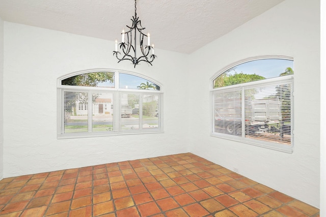 unfurnished dining area with a healthy amount of sunlight, a textured ceiling, an inviting chandelier, and a textured wall