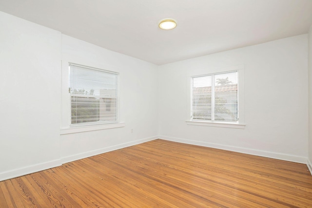 spare room featuring light wood-type flooring and baseboards