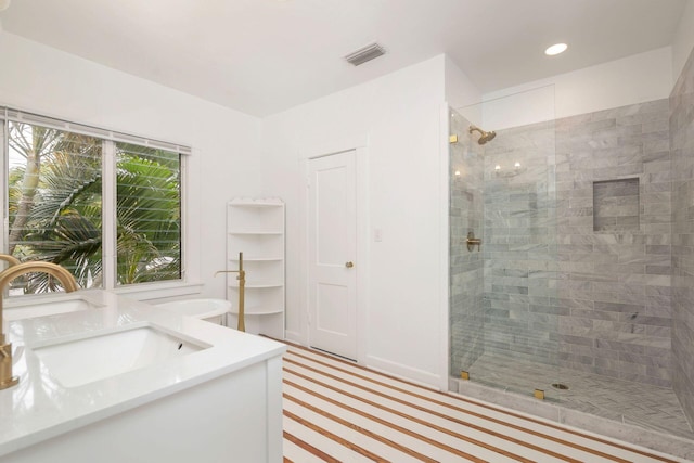 full bathroom with visible vents, a sink, a tile shower, recessed lighting, and double vanity