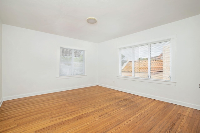 spare room with baseboards and light wood finished floors