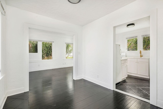 unfurnished dining area with dark wood-style floors, baseboards, and a sink