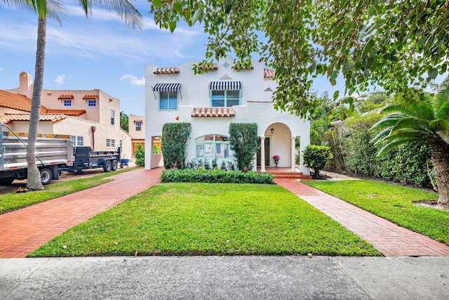 mediterranean / spanish-style house with a front lawn and decorative driveway