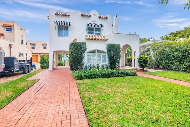 mediterranean / spanish-style house featuring stucco siding, a front yard, and a tile roof