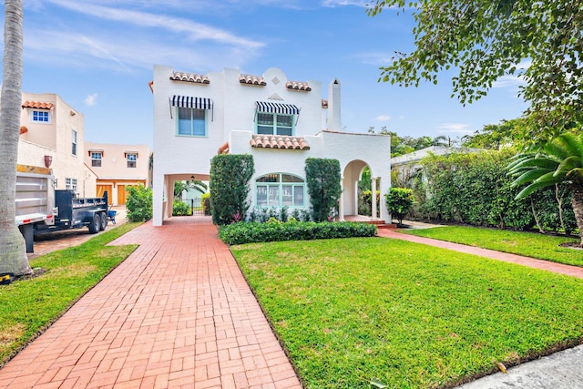 mediterranean / spanish home featuring a front lawn and stucco siding