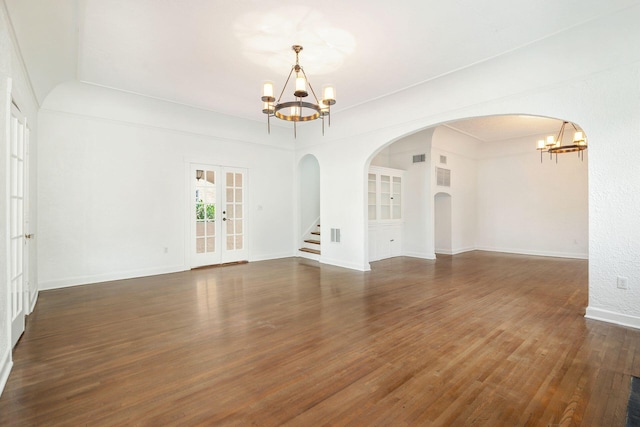 empty room with built in features, wood finished floors, baseboards, french doors, and a chandelier