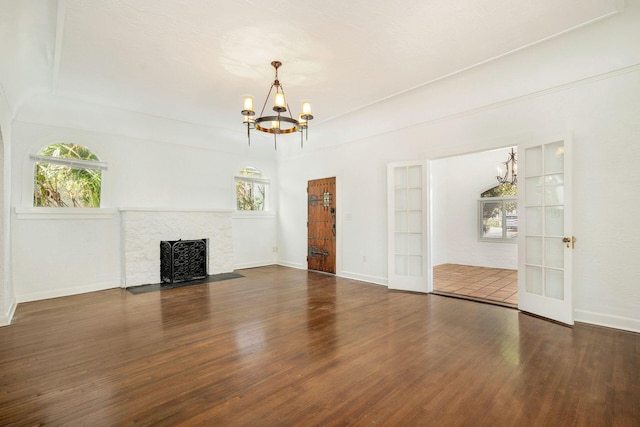 unfurnished living room featuring a healthy amount of sunlight, wood finished floors, and a chandelier