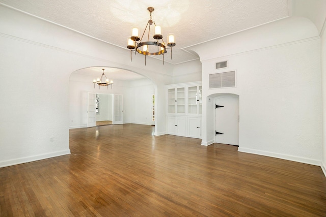 interior space featuring wood finished floors, visible vents, arched walkways, and a chandelier