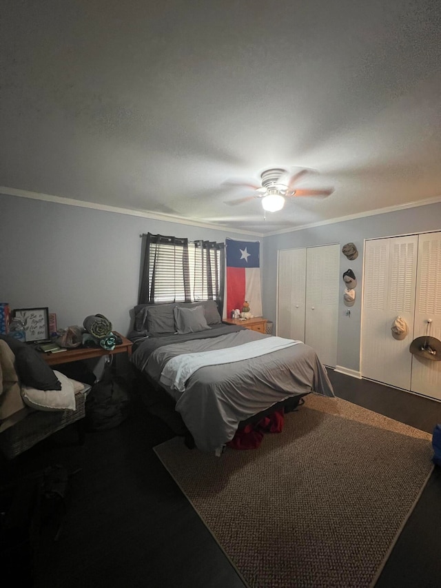 carpeted bedroom with two closets, ceiling fan, crown molding, and a textured ceiling