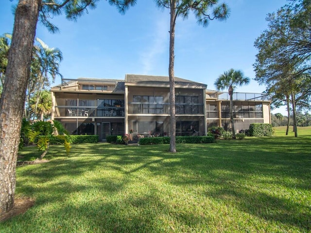 rear view of property featuring a balcony and a yard