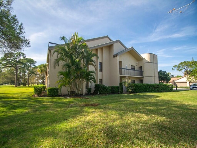 view of side of home featuring a balcony and a lawn