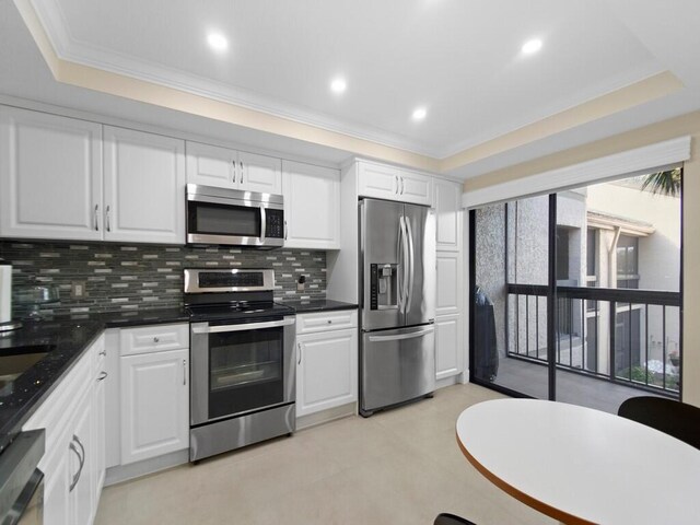 kitchen with appliances with stainless steel finishes, plenty of natural light, and a raised ceiling