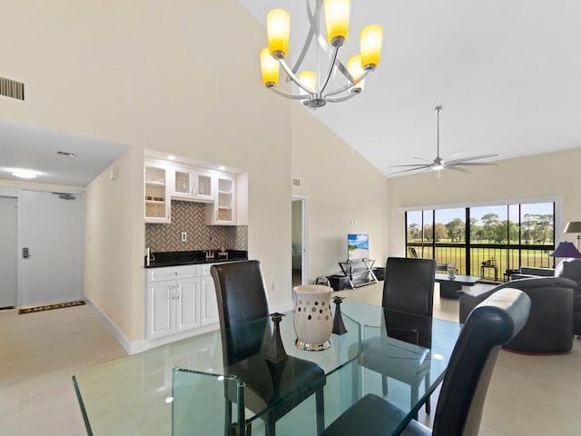 dining space featuring ceiling fan with notable chandelier and high vaulted ceiling