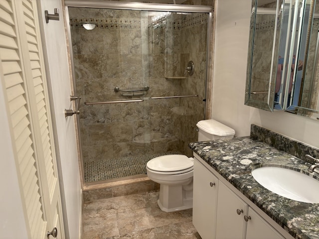 bathroom featuring a shower with door, vanity, and toilet