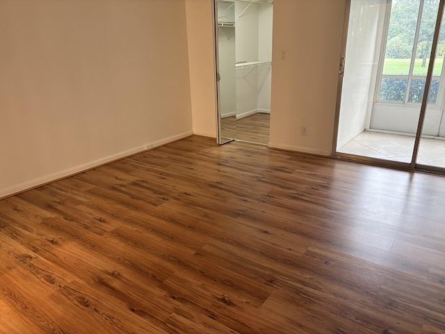 unfurnished bedroom with a walk in closet, a closet, and dark hardwood / wood-style floors