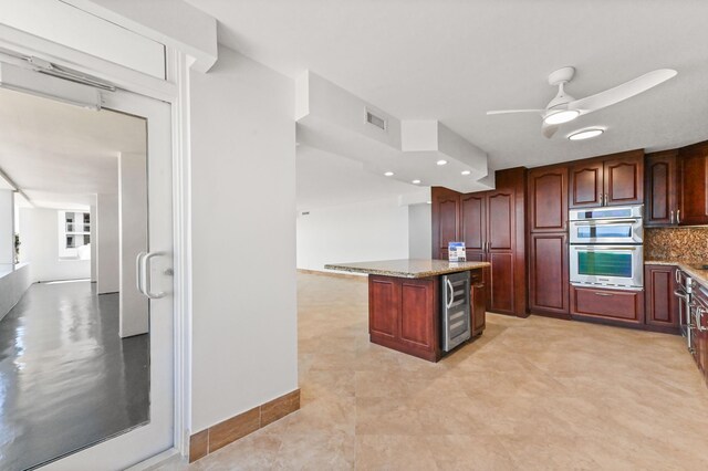 kitchen featuring light tile floors, ceiling fan, tasteful backsplash, light stone counters, and sink