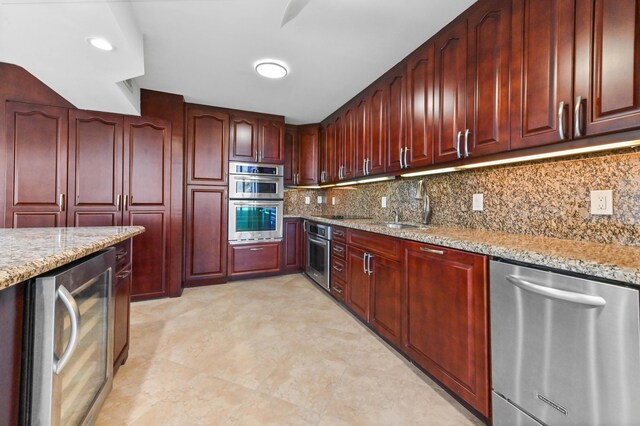 kitchen featuring light tile floors, light stone countertops, ceiling fan, stainless steel double oven, and sink