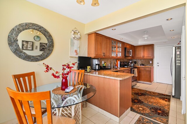 2800 S Ocean Blvd Unit 2-A, Boca Raton, FL 33432 - kitchen featuring brown cabinets, a sink, stainless steel appliances, a peninsula, and a tray ceiling