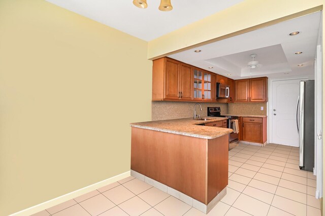 2800 S Ocean Blvd Unit 2-A, Boca Raton, FL 33432 - kitchen featuring appliances with stainless steel finishes, brown cabinets, a sink, a raised ceiling, and a peninsula