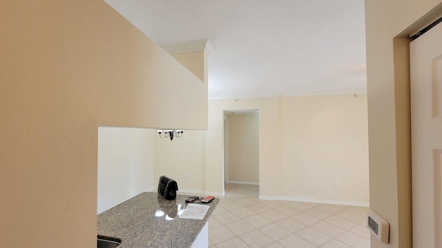 interior space featuring light tile patterned floors, crown molding, baseboards, and dark stone countertops