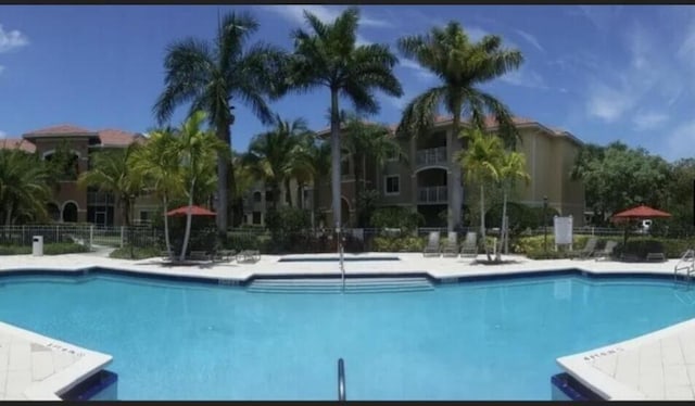 view of swimming pool featuring fence, a sink, and a patio