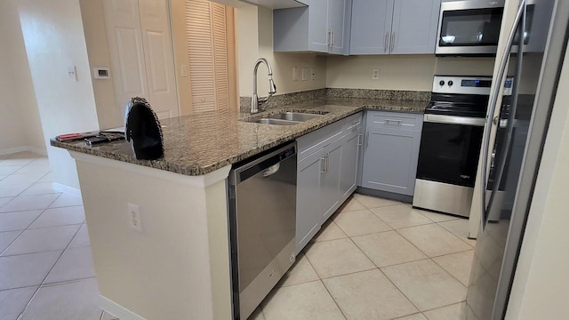 kitchen with gray cabinetry, light tile patterned floors, stainless steel appliances, sink, and kitchen peninsula