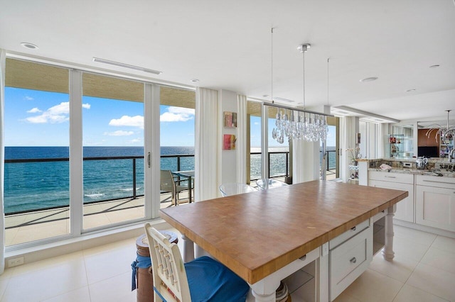 kitchen with a water view, decorative light fixtures, a center island, expansive windows, and white cabinets