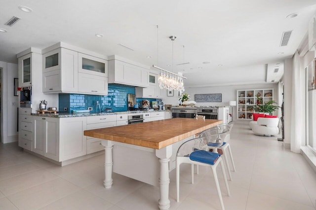 kitchen featuring pendant lighting, a breakfast bar, a center island, white cabinets, and stainless steel oven