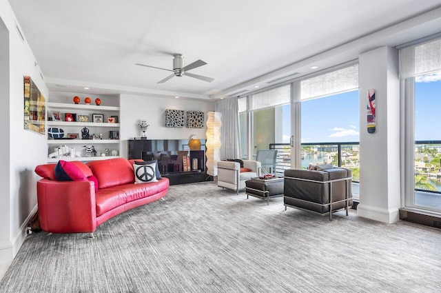 living room with ceiling fan, carpet flooring, a fireplace, and built in shelves