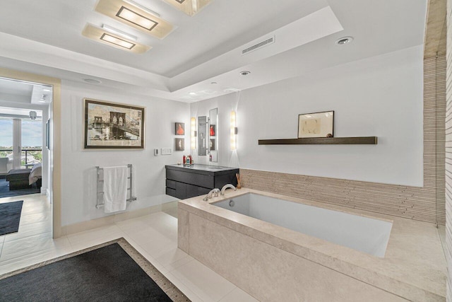 bathroom featuring tile patterned flooring, vanity, a bathtub, and a tray ceiling