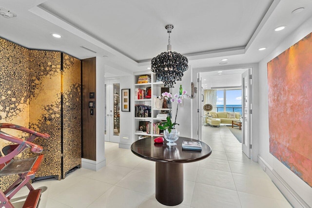 hall featuring a raised ceiling, a chandelier, and light tile patterned flooring