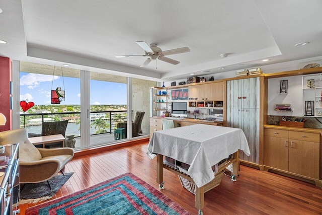 dining space featuring a tray ceiling, ceiling fan, and hardwood / wood-style flooring