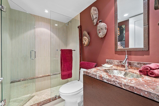 bathroom featuring a shower with door, vanity, and toilet