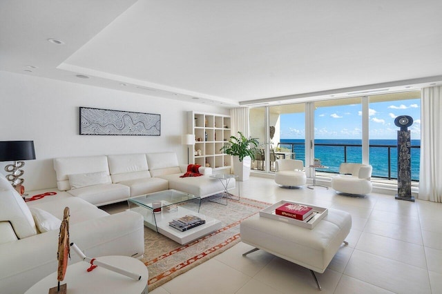 living room with a water view, floor to ceiling windows, light tile patterned flooring, and a raised ceiling