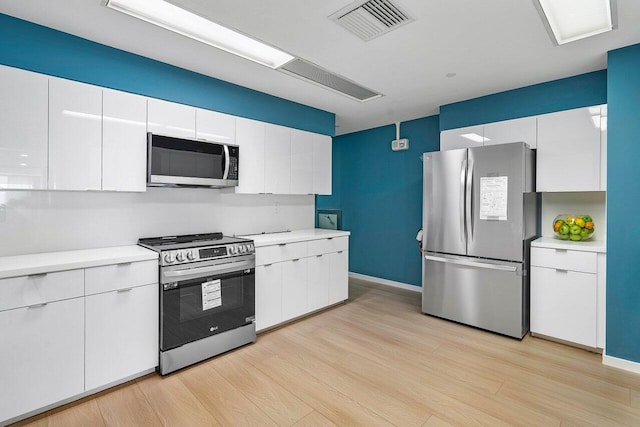 kitchen with white cabinetry, appliances with stainless steel finishes, and light hardwood / wood-style floors