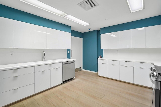 kitchen featuring appliances with stainless steel finishes, sink, white cabinets, and light hardwood / wood-style floors