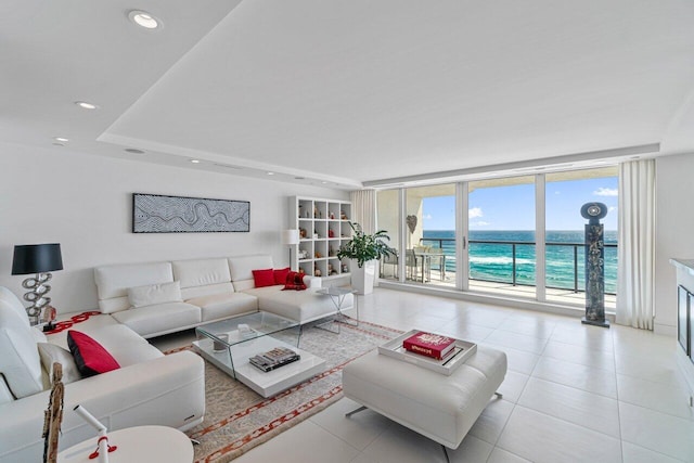 living room featuring a water view, floor to ceiling windows, and light tile patterned floors