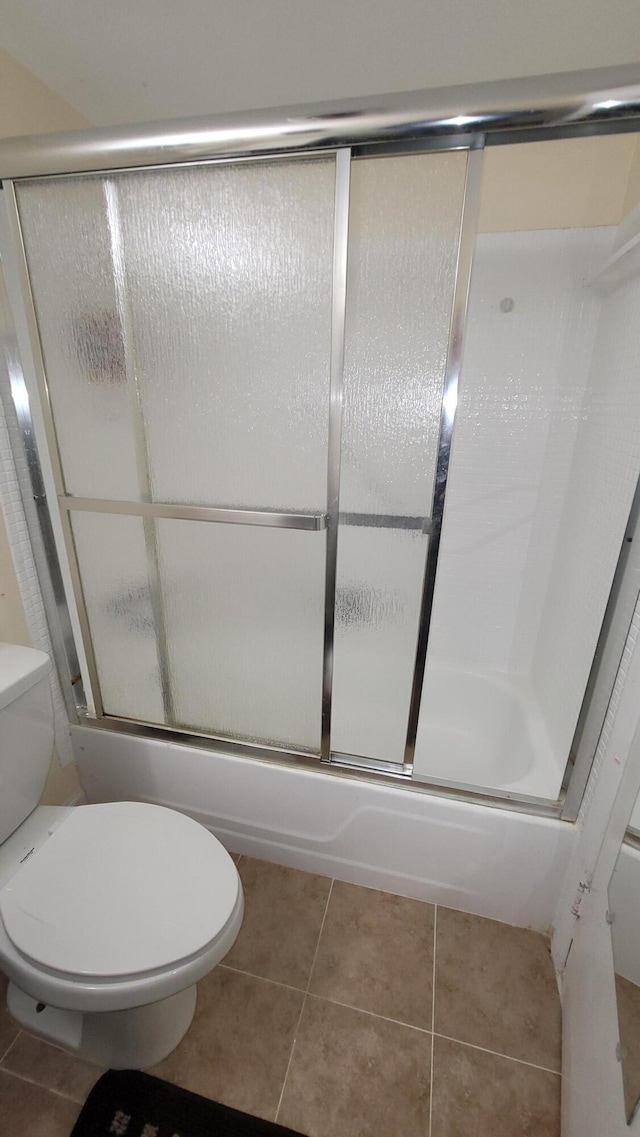 bathroom with shower / bath combination with glass door, toilet, and tile patterned floors