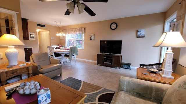 tiled living room with ceiling fan with notable chandelier