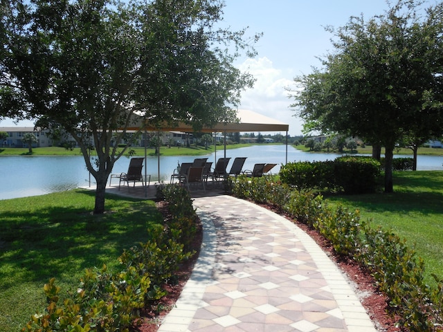 surrounding community with a water view and a yard