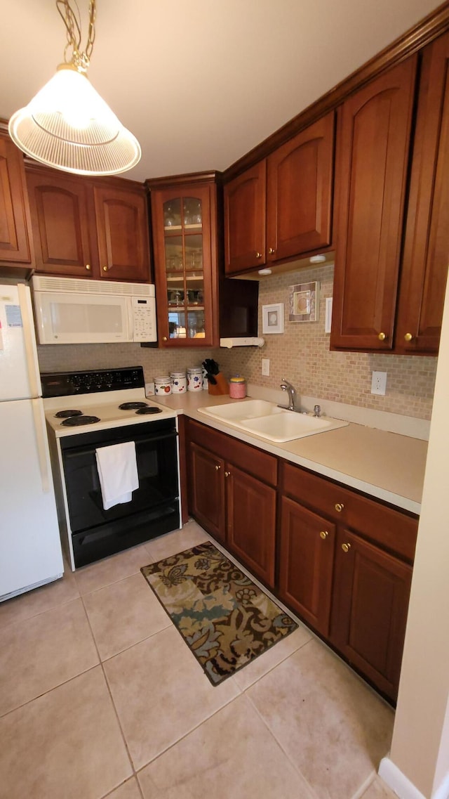 kitchen with backsplash, light tile patterned floors, white appliances, sink, and pendant lighting