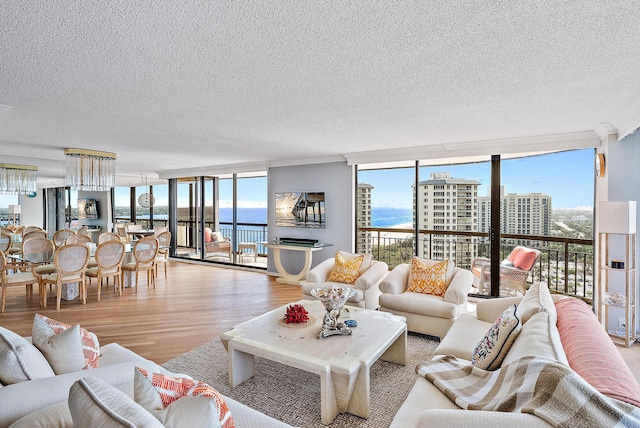 living room with floor to ceiling windows, a water view, light hardwood / wood-style floors, and a textured ceiling