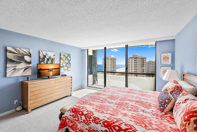 carpeted bedroom with access to exterior, floor to ceiling windows, and a textured ceiling