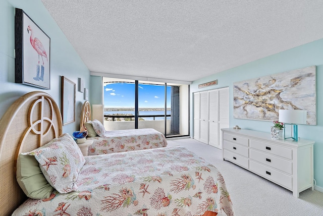 carpeted bedroom with access to outside, floor to ceiling windows, a closet, and a textured ceiling