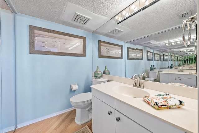 bathroom featuring vanity, wood-type flooring, a textured ceiling, and toilet