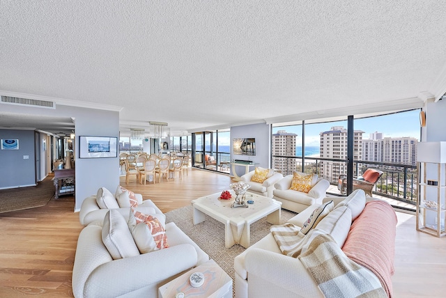 living room featuring light wood-type flooring, a wall of windows, and a textured ceiling