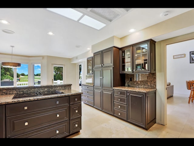 kitchen with hanging light fixtures, black electric stovetop, dark brown cabinetry, and stone counters