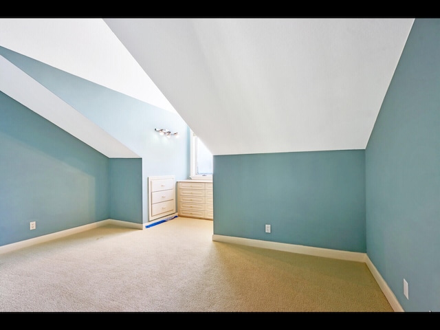 additional living space featuring lofted ceiling and carpet flooring