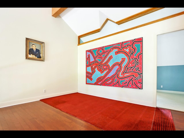 unfurnished room featuring hardwood / wood-style flooring and lofted ceiling with beams