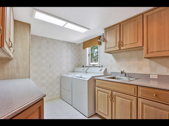 washroom featuring light tile patterned flooring, washing machine and clothes dryer, cabinets, and sink