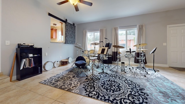 misc room with a barn door, tile patterned flooring, and ceiling fan